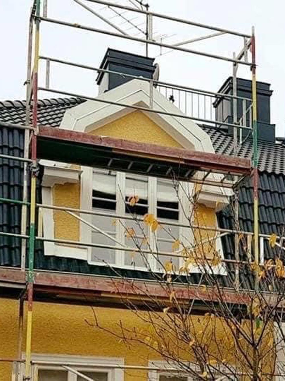 Ett gult hus med en byggställning
